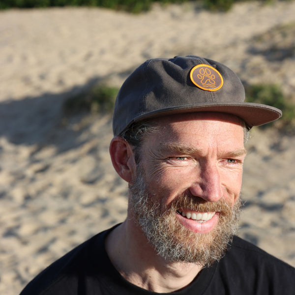 Man wearing a cap with a logo on a sandy background